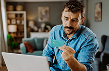 A man with a moustache looks at his Associated Bank Secured card