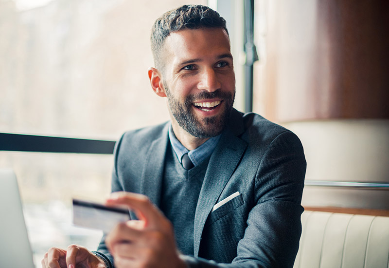 Businessman holding a credit card while working on a computer.