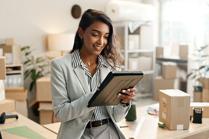 A business woman looks at her tablet to track her orders before shipping them out