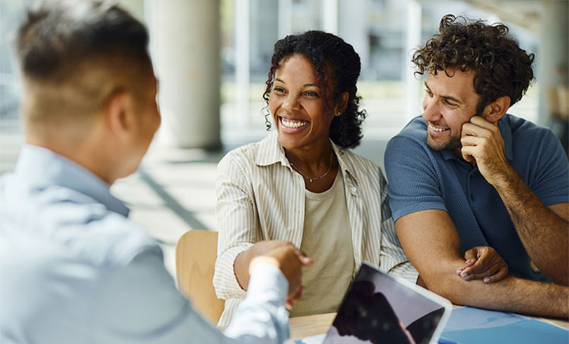 A couple shake hands with a business professional