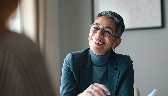 A business woman looks directly into the camera while holding her tablet