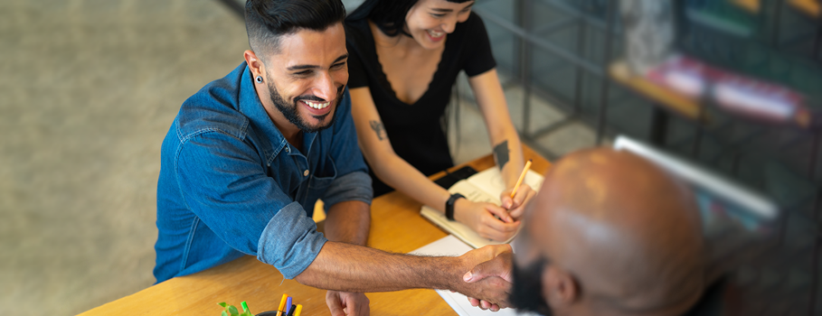 A couple shakes hands with a businessman