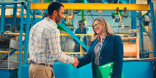 Associated Banker and Business owner shaking hands in a manufacturing setting.