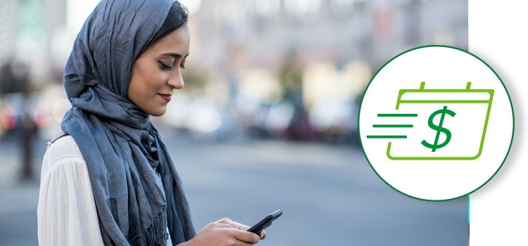 A woman looks at her phone while crossing the street