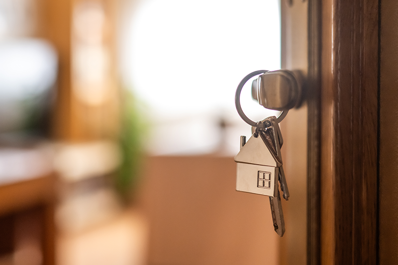 A pair of keys with a home keychain, hooked on a door handle