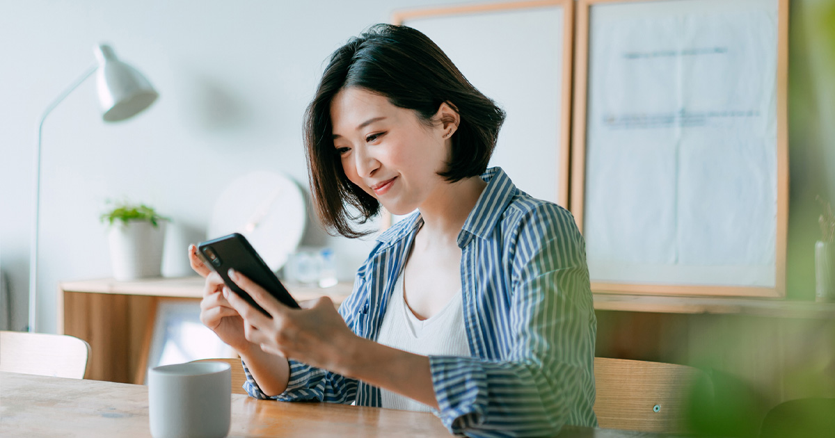 A woman smiles while looking at her phone